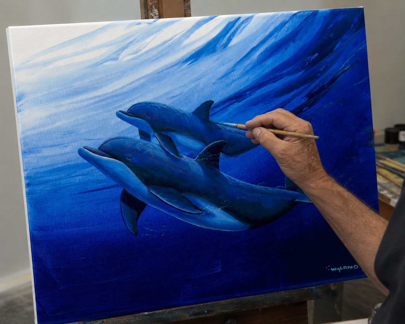 The artist painting dolphins on canvas with the embellished medium
